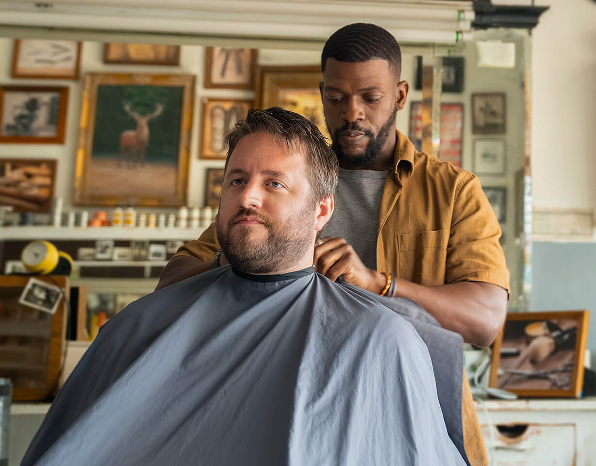 Image of barber putting cape on man